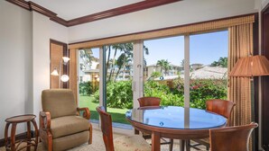 A room with a round glass table and four chairs, a sofa, and a small side table.