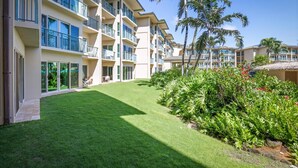 A hotel with multiple balconies, a well-maintained lawn, and tropical plants.