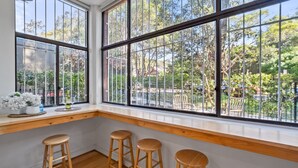 A room with large windows, wooden bar stools, and a small table with flowers and glasses. - Pet-Friendly Home Just Minutes from Bondi Beach (Bellevue Hill)