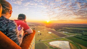 Vista panorámica de un paisaje con campos, un río y una puesta de sol.