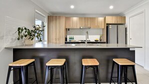 Una cocina moderna con armarios de madera, un lavamanos de acero inoxidable y una barra con taburetes.