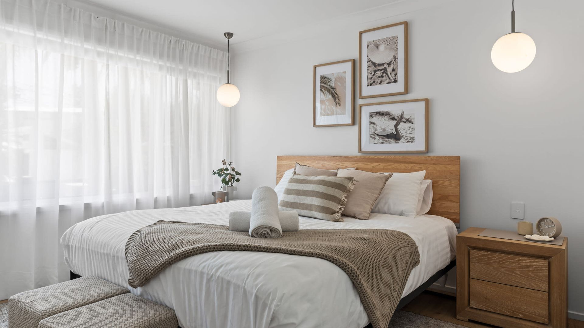 Une chambre à coucher bien rangée, avec un lit, des tables de chevet et des œuvres d’art accrochées au mur.