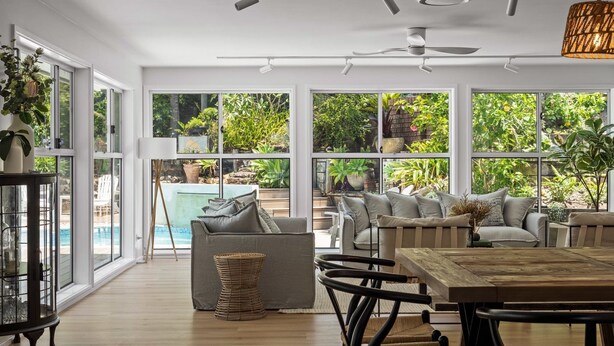 A spacious indoor area with large windows, a pool, and outdoor plants. - The Forrester Beachside Retreat Resort Style Pool Oasis (Forresters Beach)
