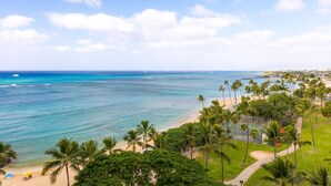 A beach with palm trees, a tennis court, and a view of the ocean. - Waikiki Shore 906 Ocean View 1 Bedroom (Honolulu)