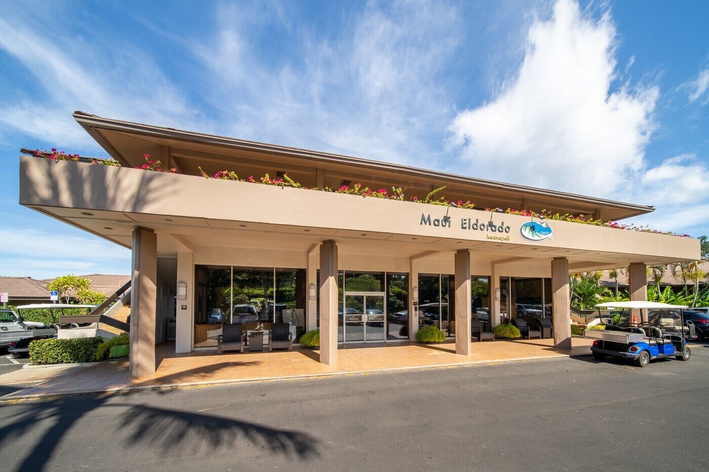 A hotel entrance with a covered outdoor seating area and a clear sky.