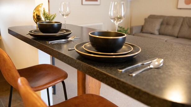 A modern kitchen with a dark countertop, two black bowls, a spoon, and a fork. - Charming 1-bedroom apartment in Jericho  (Jericho)
