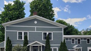 A two-story house with a gabled roof, a front porch, and a garage. - Charming 1-bedroom apartment in Jericho  (Jericho)