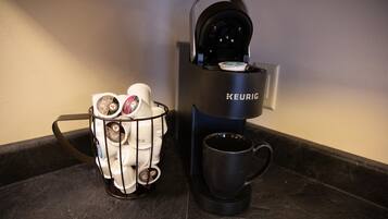 A Keurig coffee machine with a mug and a cup holder containing multiple coffee pods.