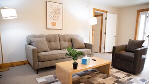 A living room with a sofa, armchair, coffee table, and a potted plant. - Charming 1-bedroom apartment in Jericho  (Jericho)
