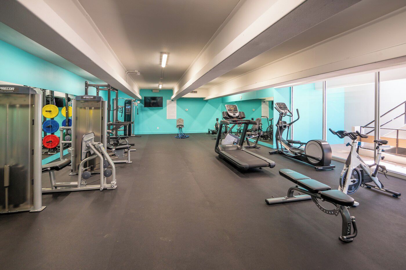 Un gimnasio con cintas de correr, bicicletas estáticas y máquinas de pesas.