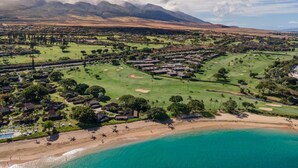 Ein Küstenort mit Golfplatz, direkt am Strand und einem Bergpanorama.