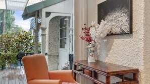 A cozy indoor seating area with a cushioned chair, a wooden table, and a vase of flowers.