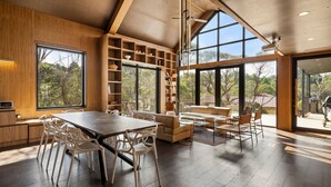 Ein modernes Interieur mit Essbereich, Bücherregalen und großen Fenstern mit Blick ins Freie.