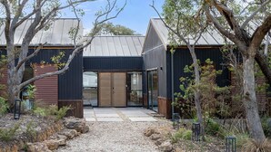 Ein modernes Haus mit einem zentralen Eingang, umgeben von Bäumen und Kies.
