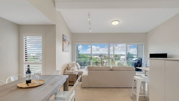 Een moderne woonkamer met een bank, eettafel en een balkon met uitzicht.