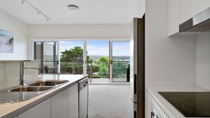 Een moderne keuken met een groot raam, een balkon en uitzicht op de omgeving.
