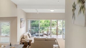 Een moderne woonkamer met een groot raam, een bank, een eettafel en een stoel.