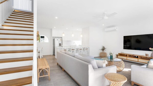 A modern living room with a sofa, a dining area, and a kitchen.