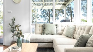 A cozy living room with a sectional sofa, a coffee table, and a potted plant. - Sunset Splash Retreat (Budgewoi)