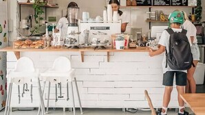 A coffee shop with a white counter, barista, and seating area. - Bobby's Binburra Beach House (Toowoon Bay)