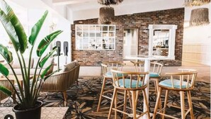 A modern interior with a brick wall, a white table with chairs, and a potted plant.