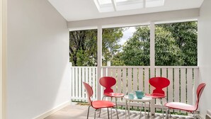 A balcony with white railings, red chairs, and a small table with a blue pitcher and a white pitcher. - The Katoomba Nest Blue Mountains Escape (Katoomba)