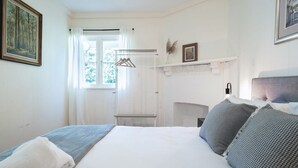 A bedroom with a bed, a window with curtains, a hanging coat rack, and a fireplace. - The Katoomba Nest Blue Mountains Escape (Katoomba)