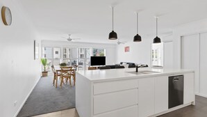 A modern kitchen with a large island, white cabinetry, and pendant lighting. - Seashells Sweet Retreat Pool, Walk to Shops & Marina (Nelson Bay)