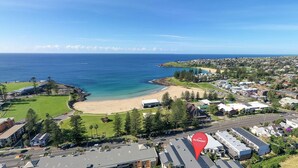 An aerial view of a coastal town with a beach, residential areas, and a golf course. - Coastal Retreat in the Heart of Kiama (Kiama)