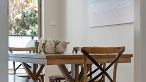 Een houten eettafel met twee stoelen, een wit decoratief voorwerp en een kleine plant.