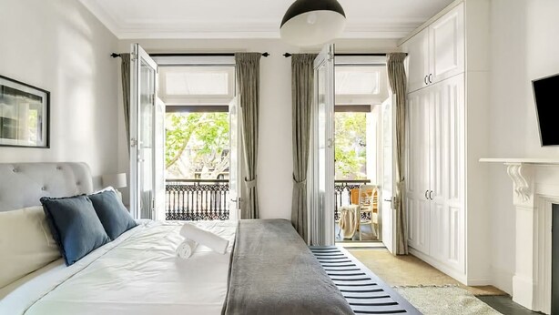 A modern bedroom with a large bed, a fireplace, and a balcony with curtains.