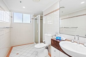 A modern bathroom with a toilet, sink, and glass shower enclosure.