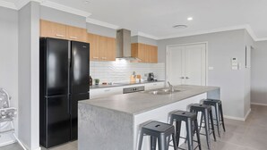 Una cucina moderna con elettrodomestici neri, un'isola bianca con sgabelli da bar e mobili in legno.