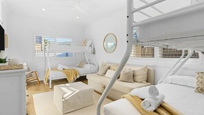 A modern, well-lit room with a bunk bed, a sofa, and a small table with a plant.