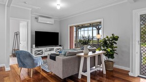 Una sala moderna con una televisión de pantalla plana, un sofá gris, un sillón azul y una mesa de centro de madera.