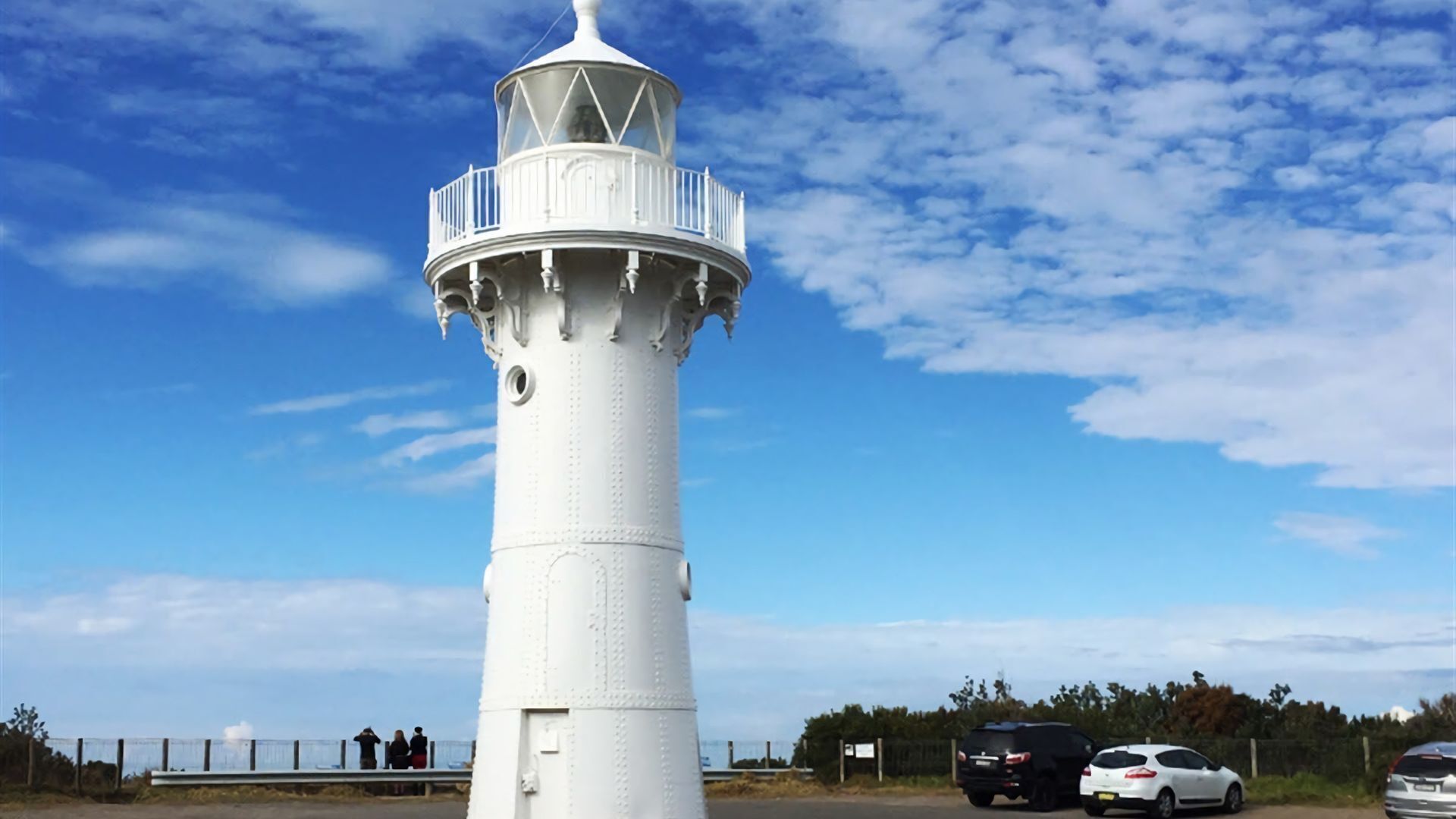 Un faro blanco con un balcón y una plataforma de observación circular.