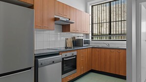 Une cuisine avec des meubles en bois, un lave-vaisselle en acier inoxydable, un four, un four à micro-ondes et une fenêtre à carreaux.