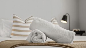 Un lit bien fait, avec une serviette blanche enroulée, des oreillers à rayures et une lampe de chevet.