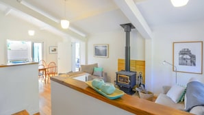 Un salón moderno con una mesa de comedor de madera, un sofá y un techo alto con vigas a la vista.