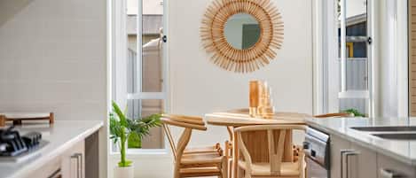 Een moderne keuken met een ronde houten tafel, twee stoelen, een potplant en een bijzondere houten spiegel aan de muur.