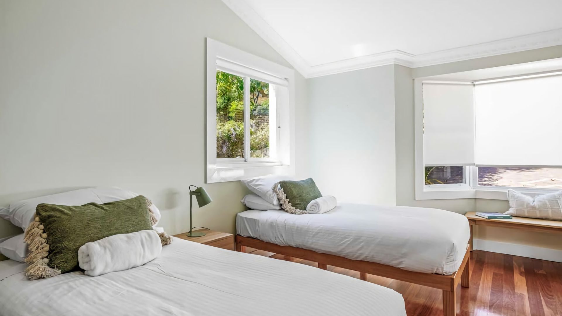 Un dormitorio con dos camas, una ventana con vistas a zonas verdes y suelo de madera.
