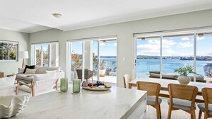 Een ruime woonkamer met een groot raam dat uitzicht biedt op zee en de stad.