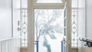 Puerta con paneles de vidrio y vista a un árbol cubierto de nieve.