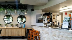 A restaurant interior with wooden cabinets, hanging plants, and a counter with a menu sign. - Kilaben Bay Escape - Minutes to the Water (Kilaben Bay)
