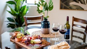 A round glass table with a variety of cheeses, fruits, and nuts, accompanied by two glasses of red wine and a bottle of wine. - Kilaben Bay Escape - Minutes to the Water (Kilaben Bay)