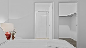 Ein Hotelzimmer mit Bett, Nachttisch mit Lampe und Kleiderschrank.