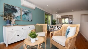 A cozy living room with a white cabinet, wicker furniture, and two large abstract paintings.