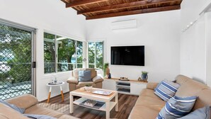 Un salon moderne doté d’une grande fenêtre, d’un téléviseur à écran plat et d’un plafond en bois.