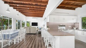 Une cuisine moderne avec des armoires blanches, un plafond en bois et un grand îlot central.