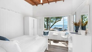 Une chambre avec un lit, un bureau et une vue sur la mer.